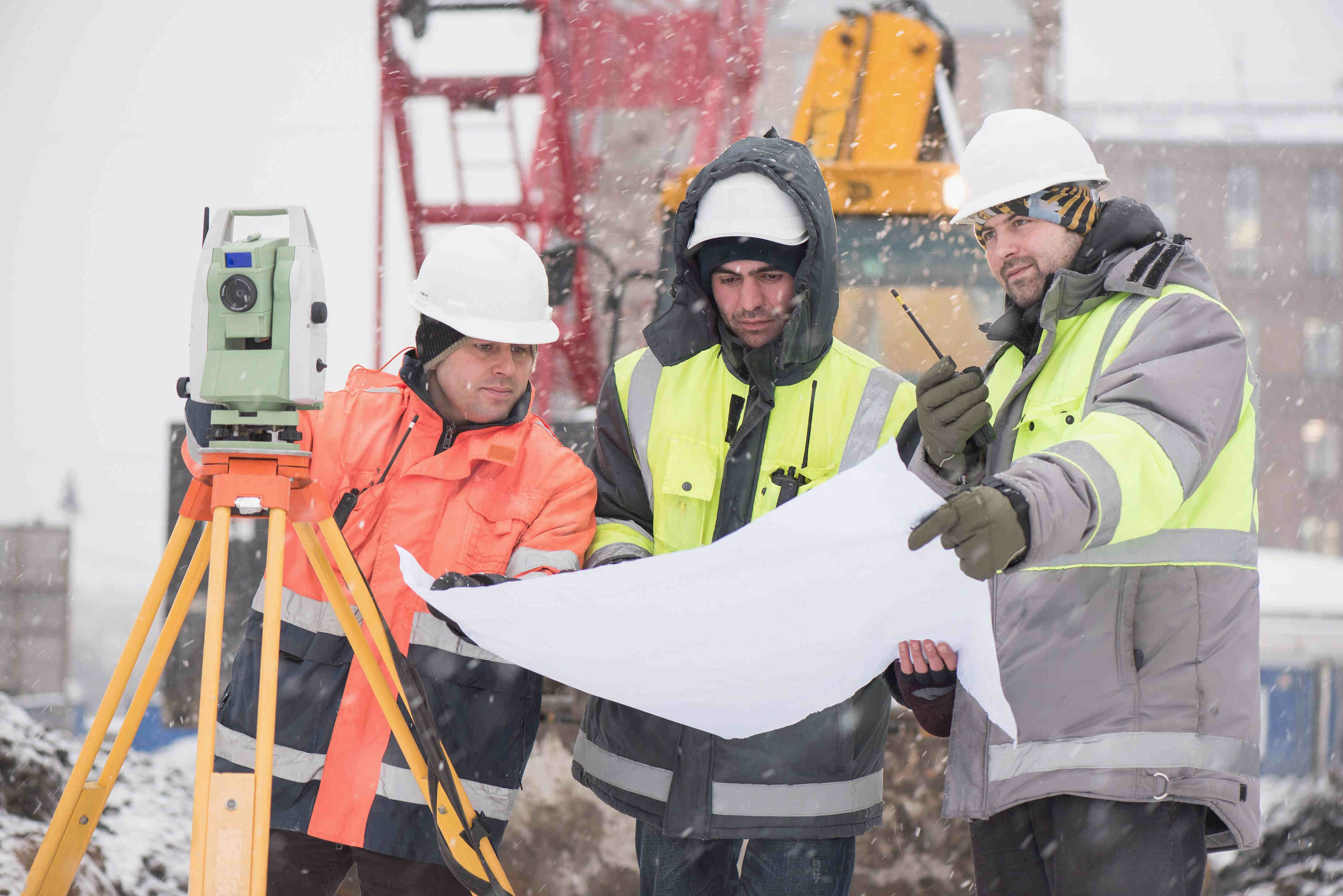 construction workers at construction site are inspecting ongoing production according to design drawings.